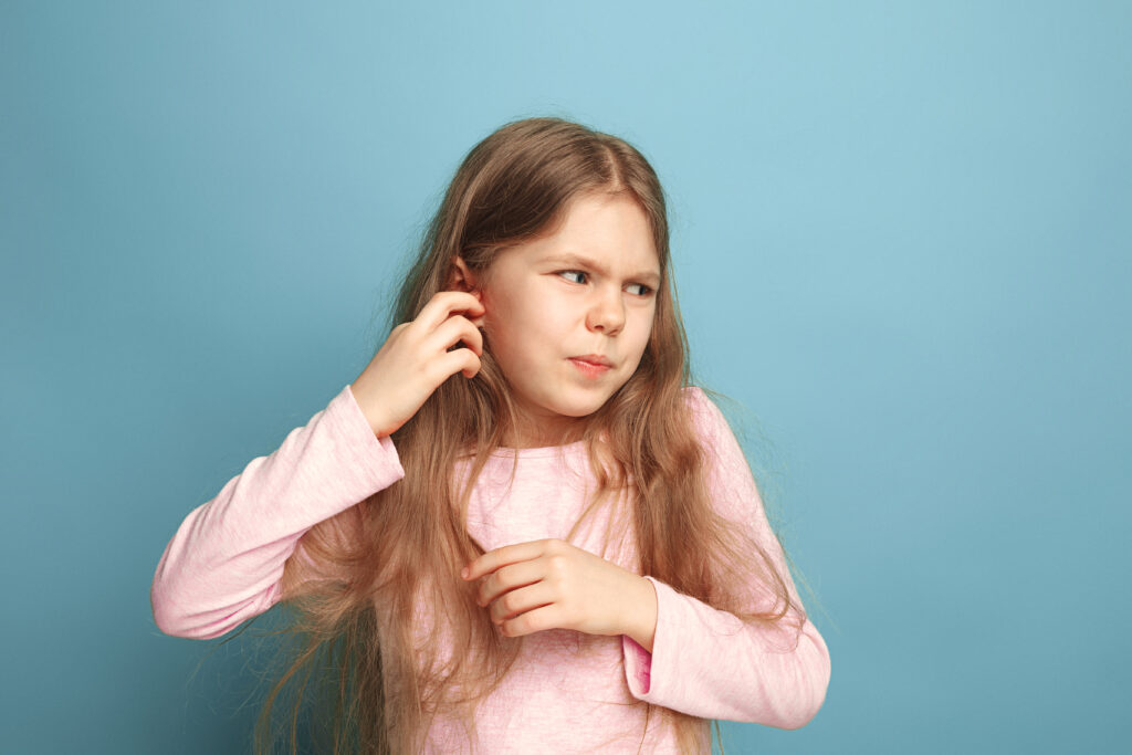 The Ear ache. Teen girl on a blue background. Facial expressions and people emotions concept - Dr. Manasi Mehra